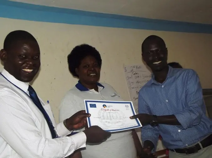 Lira Branch Manager Sam Ebinu (L) and Adekokwok Sub-County Chief Grace Lillian Ochare handing over a certificate to one of the participants.