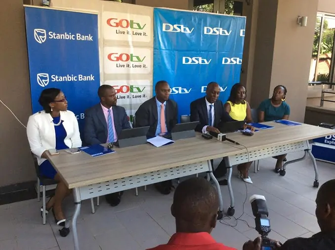 Charles Hamya, MultiChoice Uganda's general manager speaks at the press conference where the partnership with Stanbic Bank was announced. Seated next to him (L) is Stanbic CEO Patrick Mweheire. Photo: Uganda Business News