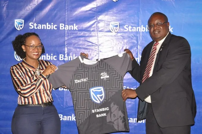 A Stanbic Bank Uganda official and an official from Black Pirates Rugby Club holding a club shirt