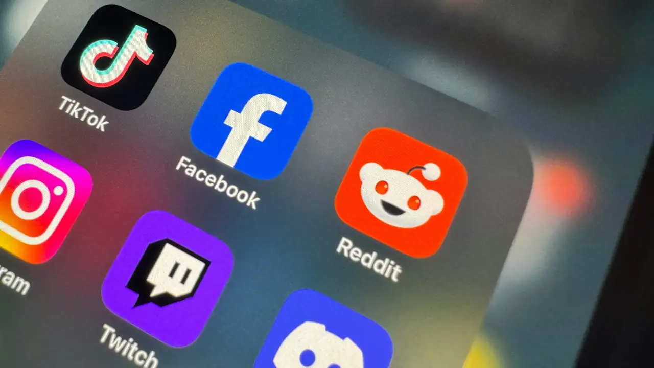 A close-up of a smartphone displaying social media icons on its screen.