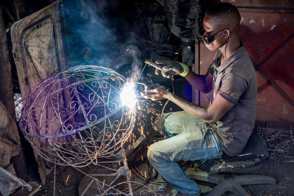 A young man welding items at a market in Bamako, Mali