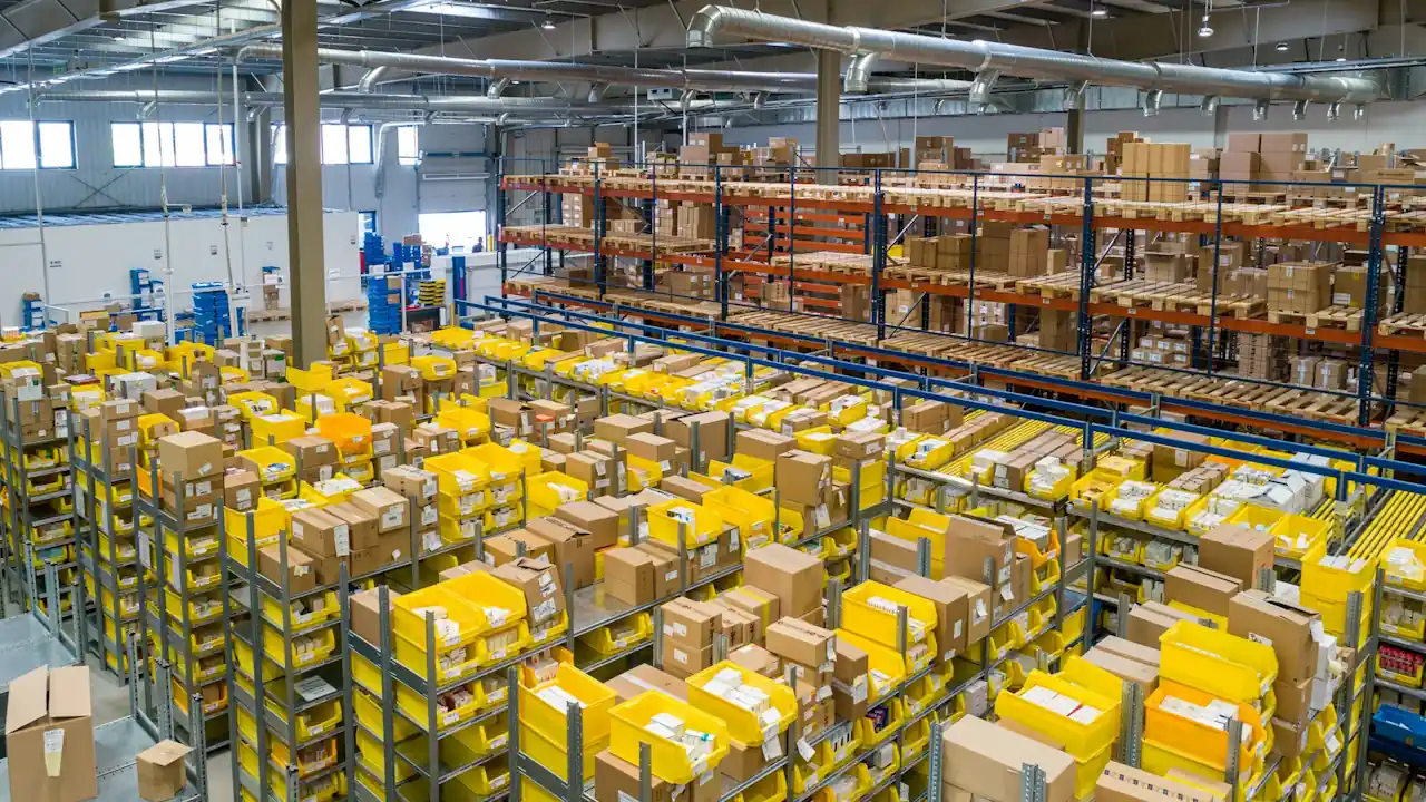An industrial warehouse | Uganda Business News High-angle view of an expansive industrial warehouse showing systematic stock accumulation in yellow bins and tiered racking.