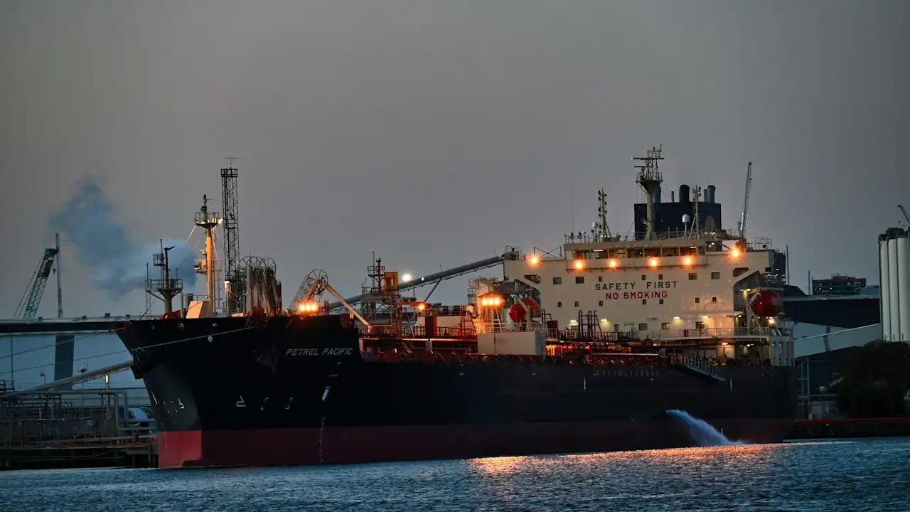 The oil and chemical tanker Petrel Pacific moored at a terminal during twilight, discharging ballast water.