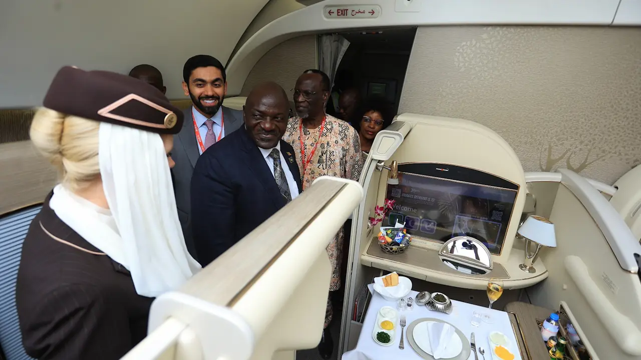 Four men and a woman wearing a flight attendant's uniform stand in an airliner cabin. To celebrate 25 years of flying in Uganda, Emirates operated a special one-off flight to Entebbe on its fully refurbished four-class Boeing 777 aircraft. This was followed by a static display to showcase the airline's latest offerings and greatest features. During the static tour, guests experienced the refurbished Boeing 777, including the next-generation cabins, latest sophisticated design, and the highly acclaimed Premium Economy Cabin, unveiled in Uganda for the first time.