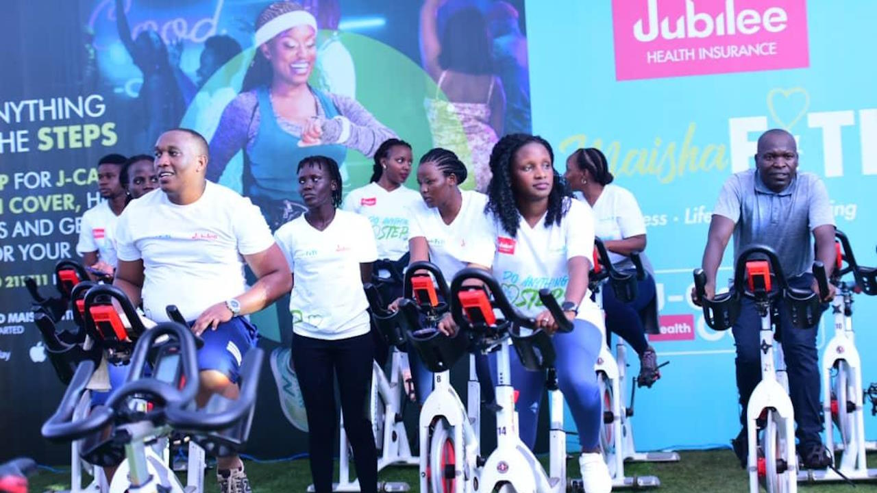 Individuals participating in a group exercise session on stationary bikes at an event unveiling a new wellness programme by Uganda's Jubilee Health Insurance