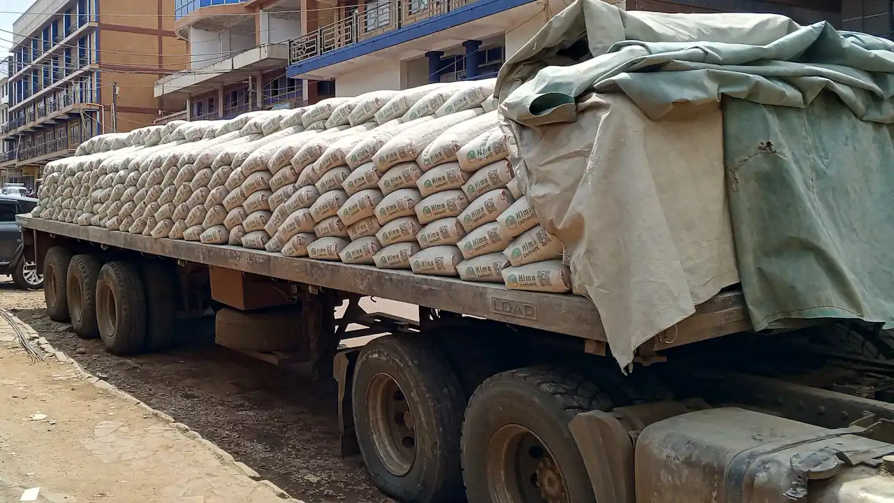 A flatbed lorry loaded with stacks of cement bags on a street in Jinja, Uganda.