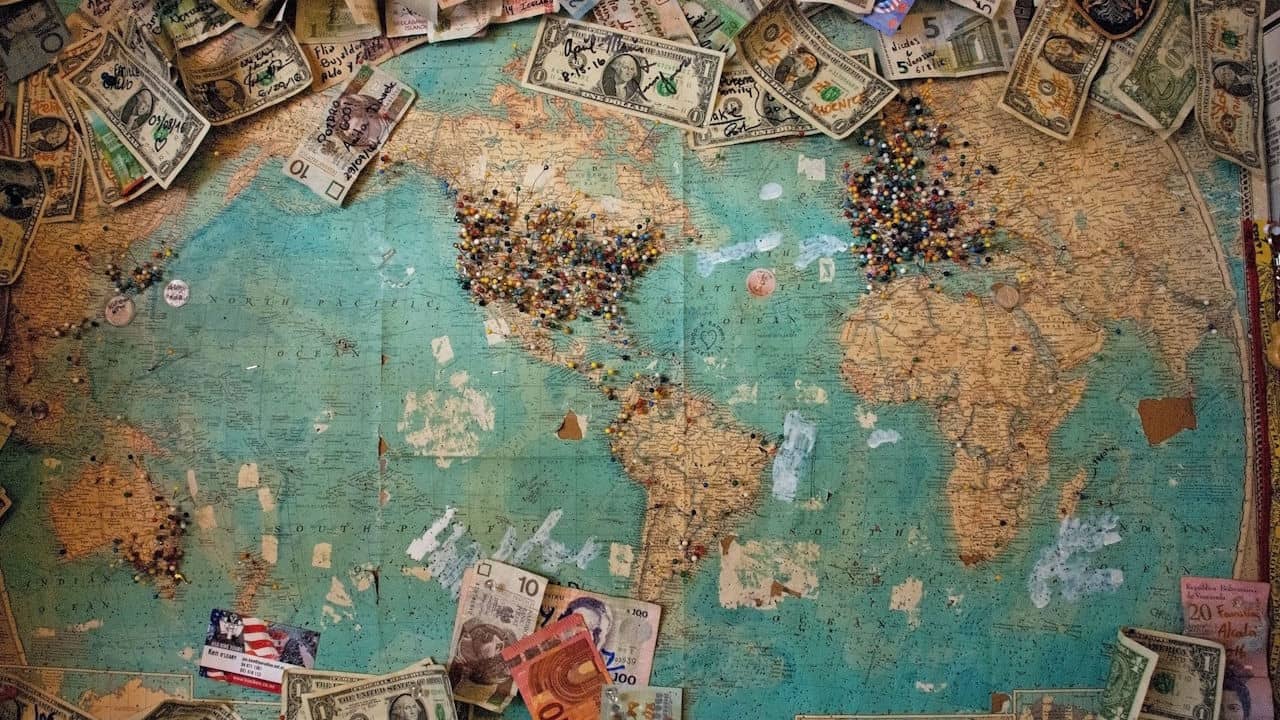 A map displayed in a shop in the US shows pins and currencies left by visitors from around the world. Based on the number of pins on the map, it seems that most visitors are from the United States, followed by Western Europe.
