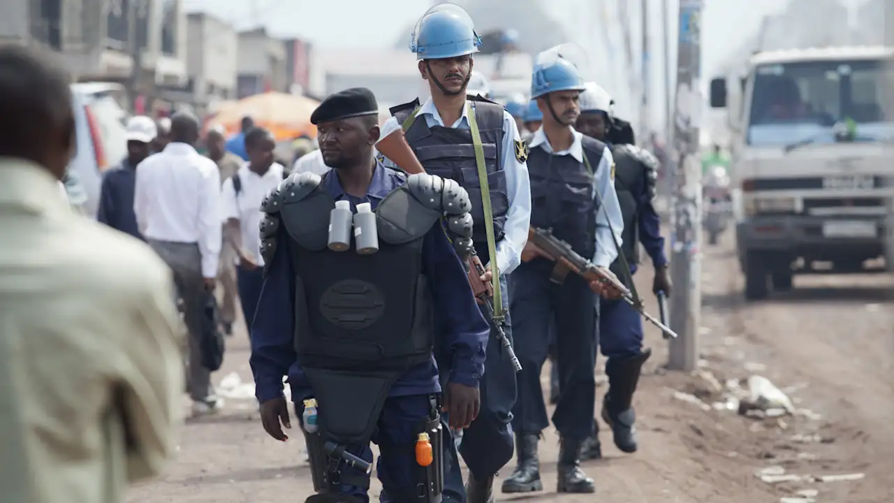 Four officers from a joint police force comprising elements of the United Nations Police and the Congolese National Police, armed with guns and batons, patrol a busy area of Goma, a city in the North Kivu province of the Democratic Republic of the Congo, in December 2011.