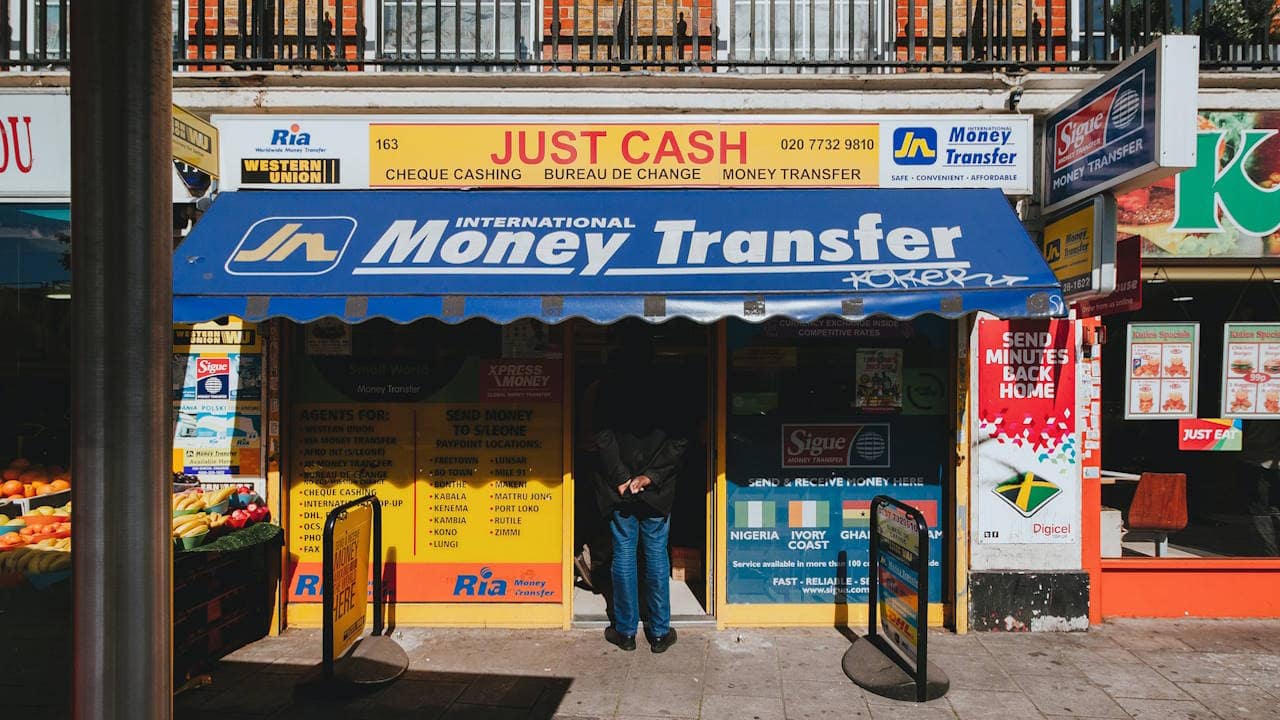 Street scene of a man waiting in line at a money transfer shop in London