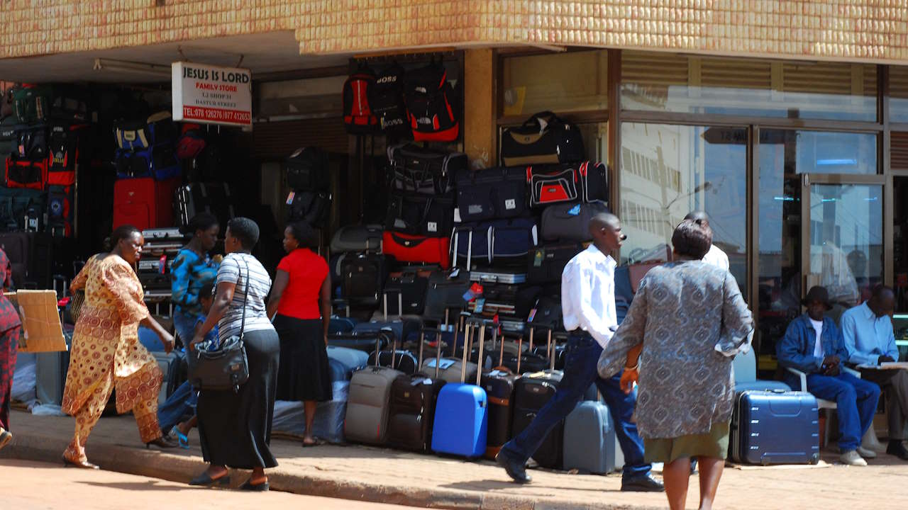 People walking past a luggage shop in downtown Kampala.
