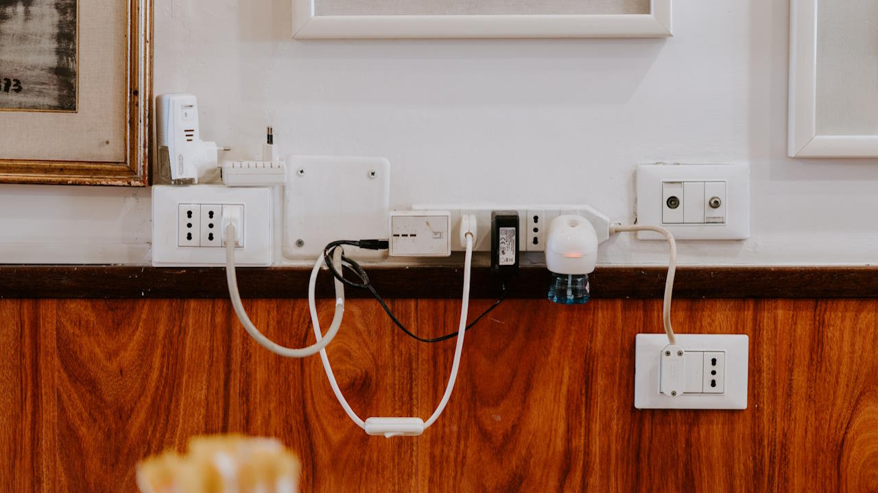 Electricity plugs on a wall, and phone chargers, in an interior setting