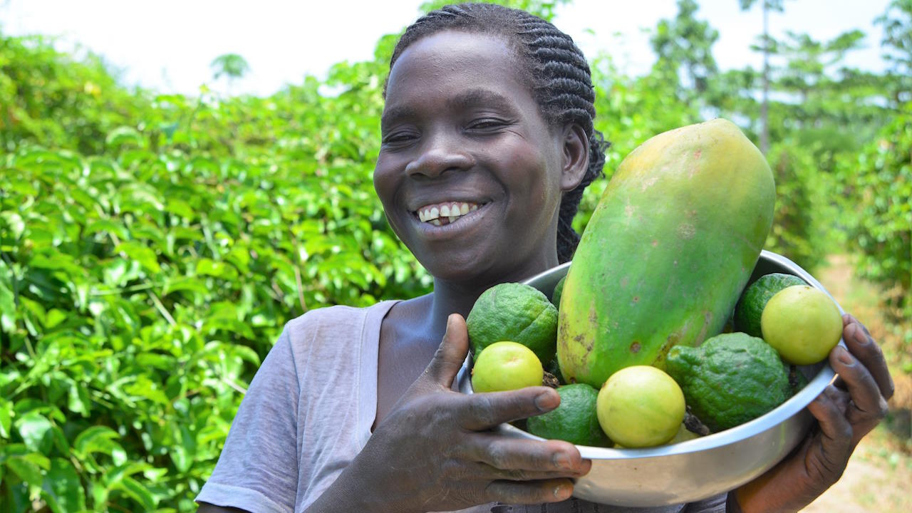Smiling farmer holding up harvest from her fruit garden