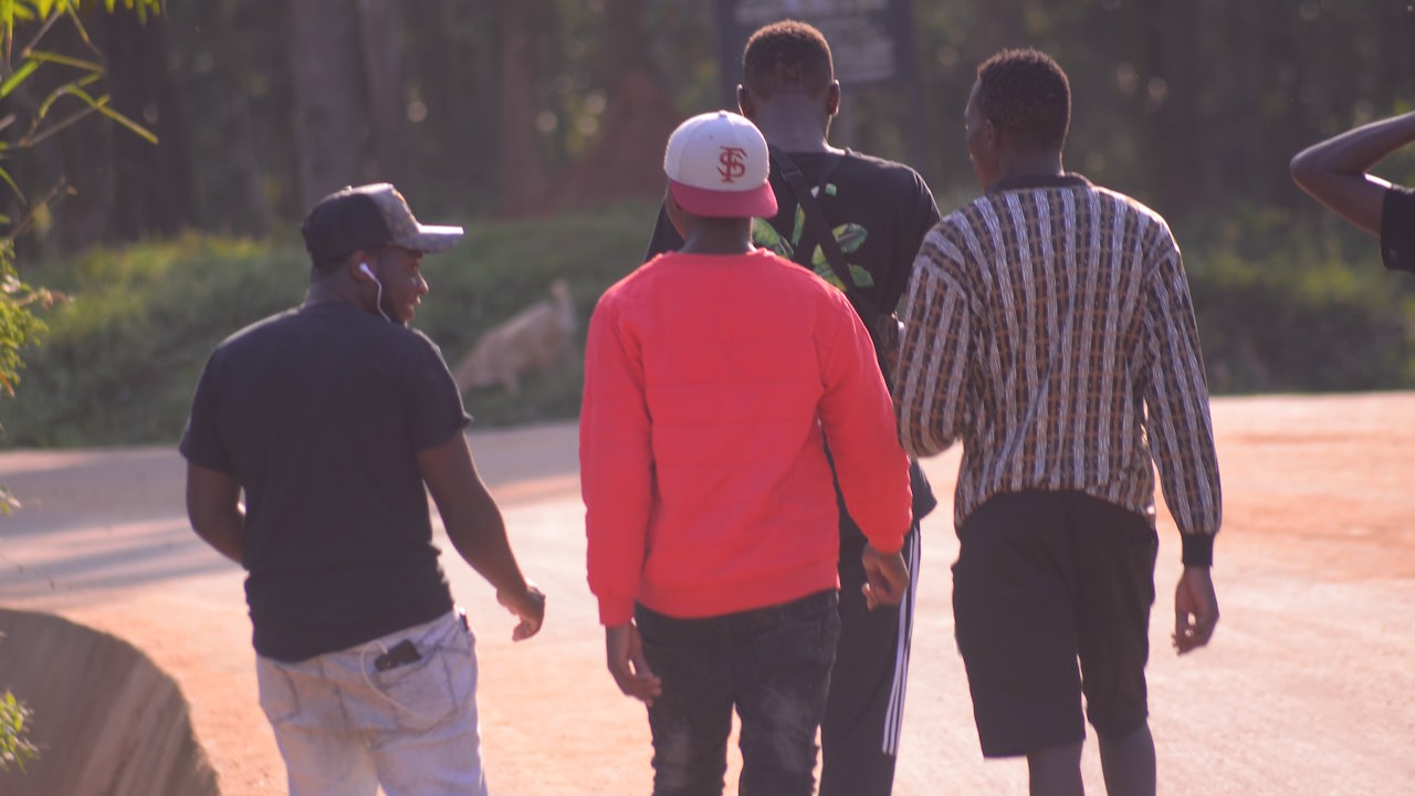 Four young men walking down a road in Kampala