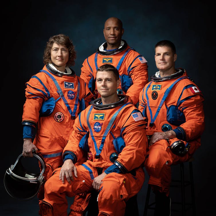 file-20230403-16-y1n19n | Uganda Business News Four astronauts in orange space suits with their helmets off.
